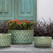 Oriel Planter, Low in glazed sea green on concrete filled with plants.