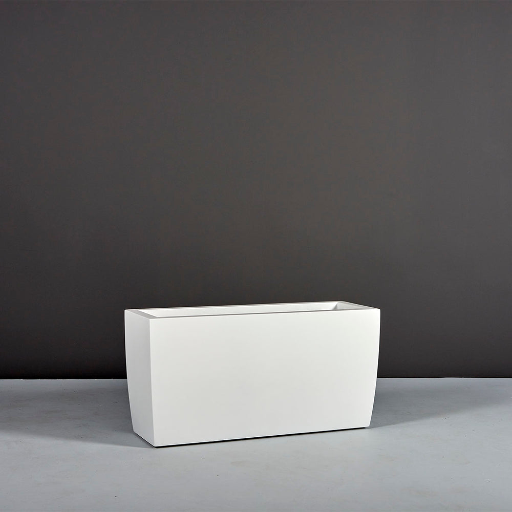 Panama Tapered Rectangle Planter on concrete filled with plants against gray background.