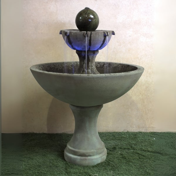 Ronde Two Tier Fountain on grass against brown background.