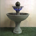 Ronde Two Tier Fountain on grass against brown background.