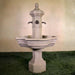 Roubaix Fountain for Rustic Spouts on grass against cream wall.