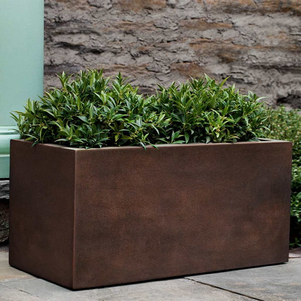 Sandal Planter 361818 S/1 in rust lite on concrete filled with plants.