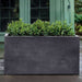 Sandal Planter 482424 S/1 in charcoal premium lite on concrete filled with plants.