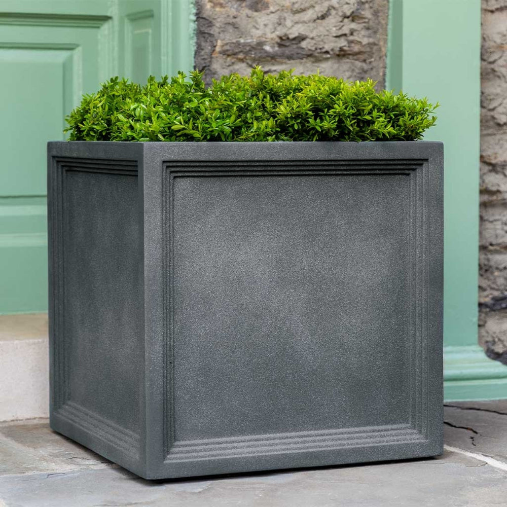 Campania International Sandhurst Square Planter, Large on concrete filled with plants.
