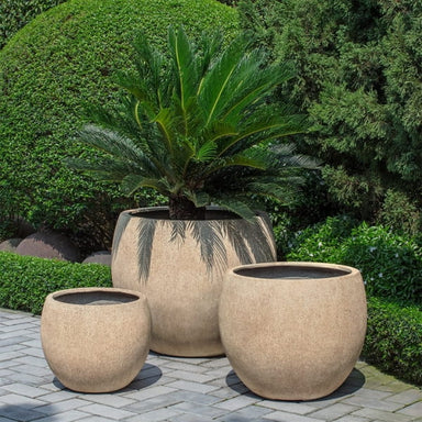 Sfera Planter, Large on concrete filled with plants.