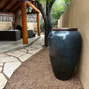 Short Sora Jar Planter Rustic Blue on gravel beside a wall