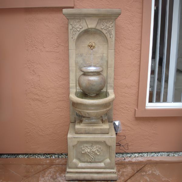 St. Helena Urn Fountain against brown wall.