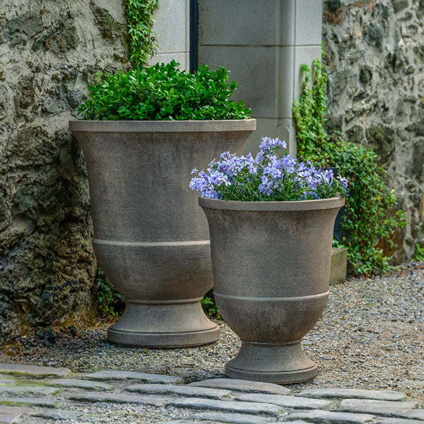 Textured Pascal Urn, Large on gravel filled with plants in the backyard