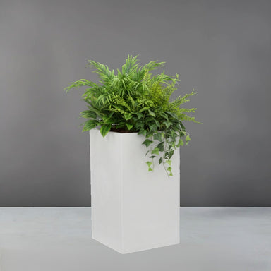Torino Corner Fiberglass Planter filled with plants against gray background.