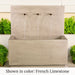 Tribus Wall Fountain in french limestone color in action beside green plants.