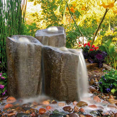 Triple Column Fountain Kit in mixed pebbles in the backyard