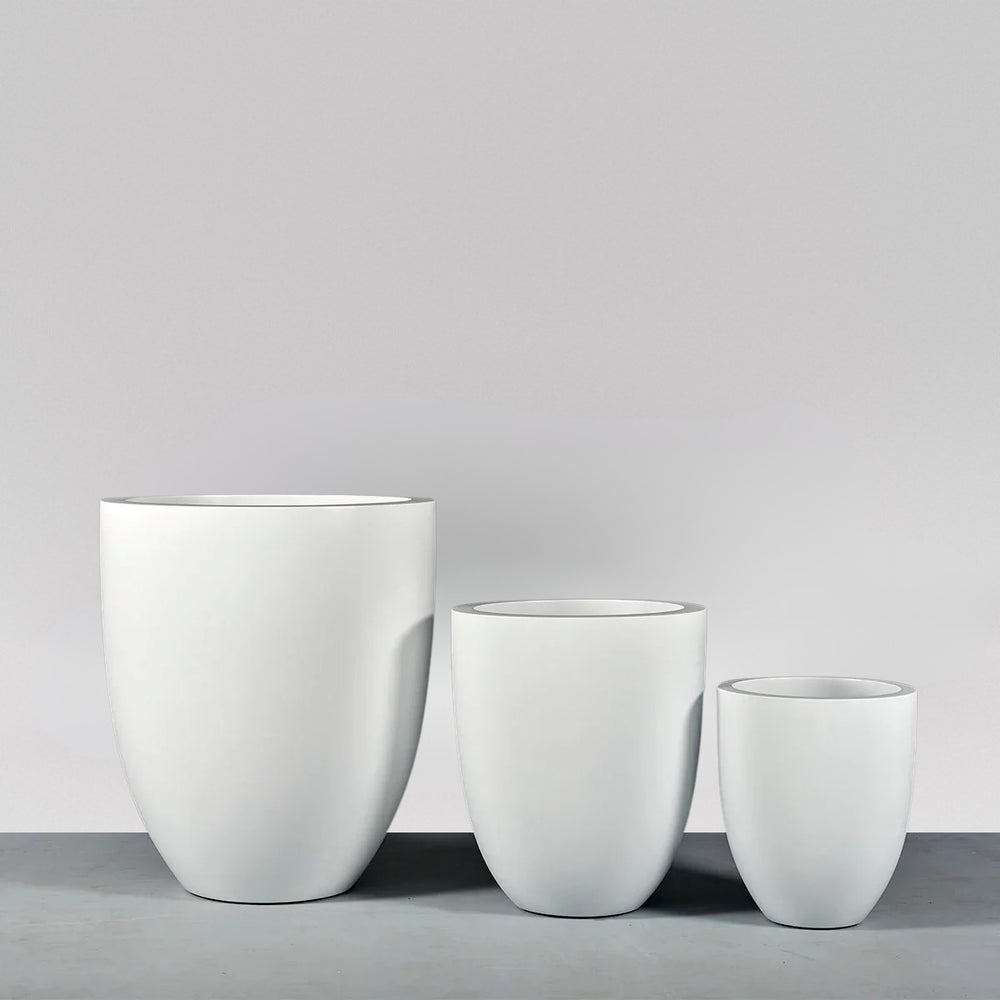 Valencia Tapered Round Fiberglass Planter on concrete shown with different sizes.