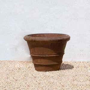 Classic Rolled Rim 18.25 Planter on gravel against wall in the backyard