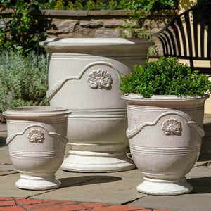 Coquille Anduze Urn S/3 Antique White filled with plants in the backyard