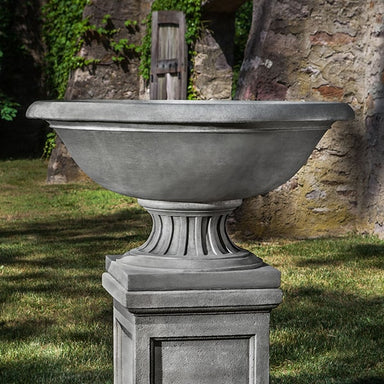 Fonthill Urn on pedestal against concrete wall with leaves upclose