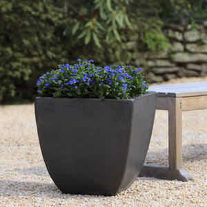 Mika Square Planter - Graphite S/3 on gravel filled with violet flowers