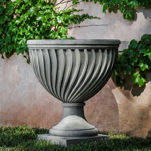 Quadrille Urn on grass against wall with leaves