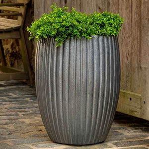 Riva Planter Graphite S/2 filled with plants near a wooden chair