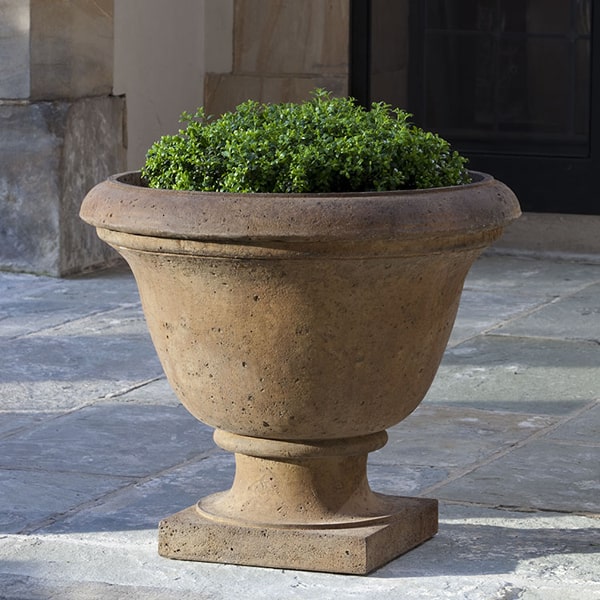 Rustic Greenwich Urn on concrete patio filled with plants