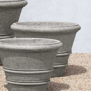 Rustic Rolled Rim 27 Planter filled with plants against white wall 