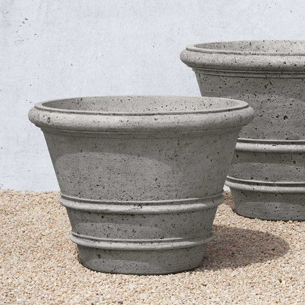 Rustic Rolled Rim 31.5 Planter filled with plants against white wall 