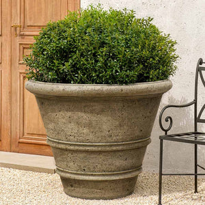 Rustic Rolled Rim 40 Planter filled with plants near a door