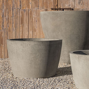 three different sized greystone planters on gravel near wall