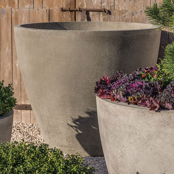 Two large greystone planters against wall